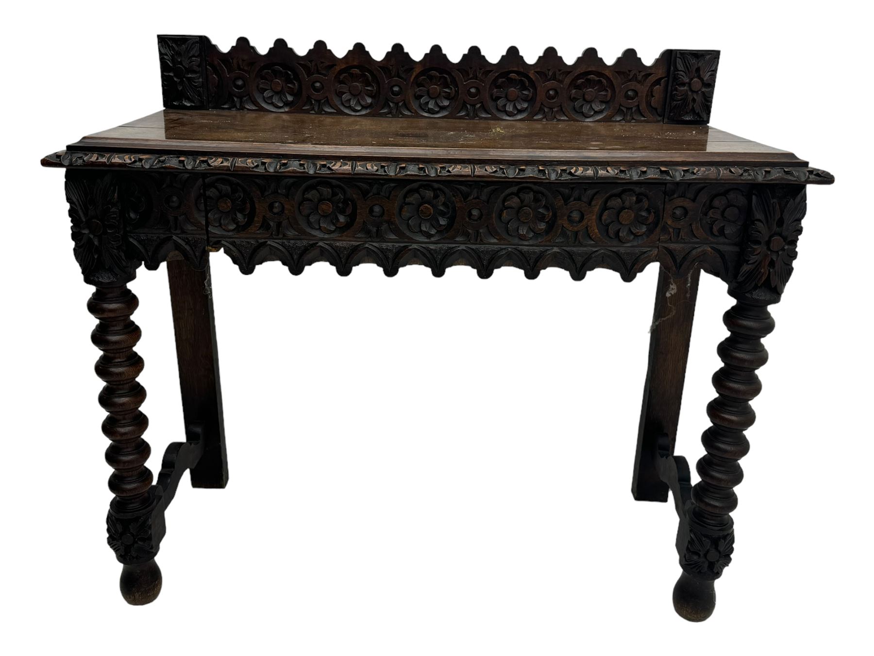 Victorian Gothic revival style carved oak console table, rectangular top with carved edge and raised back gallery, over deeply carved apron with floral and foliate motifs and central drawer, barley twist front supports and plain rear supports united by shaped stretchers, on front bun feet