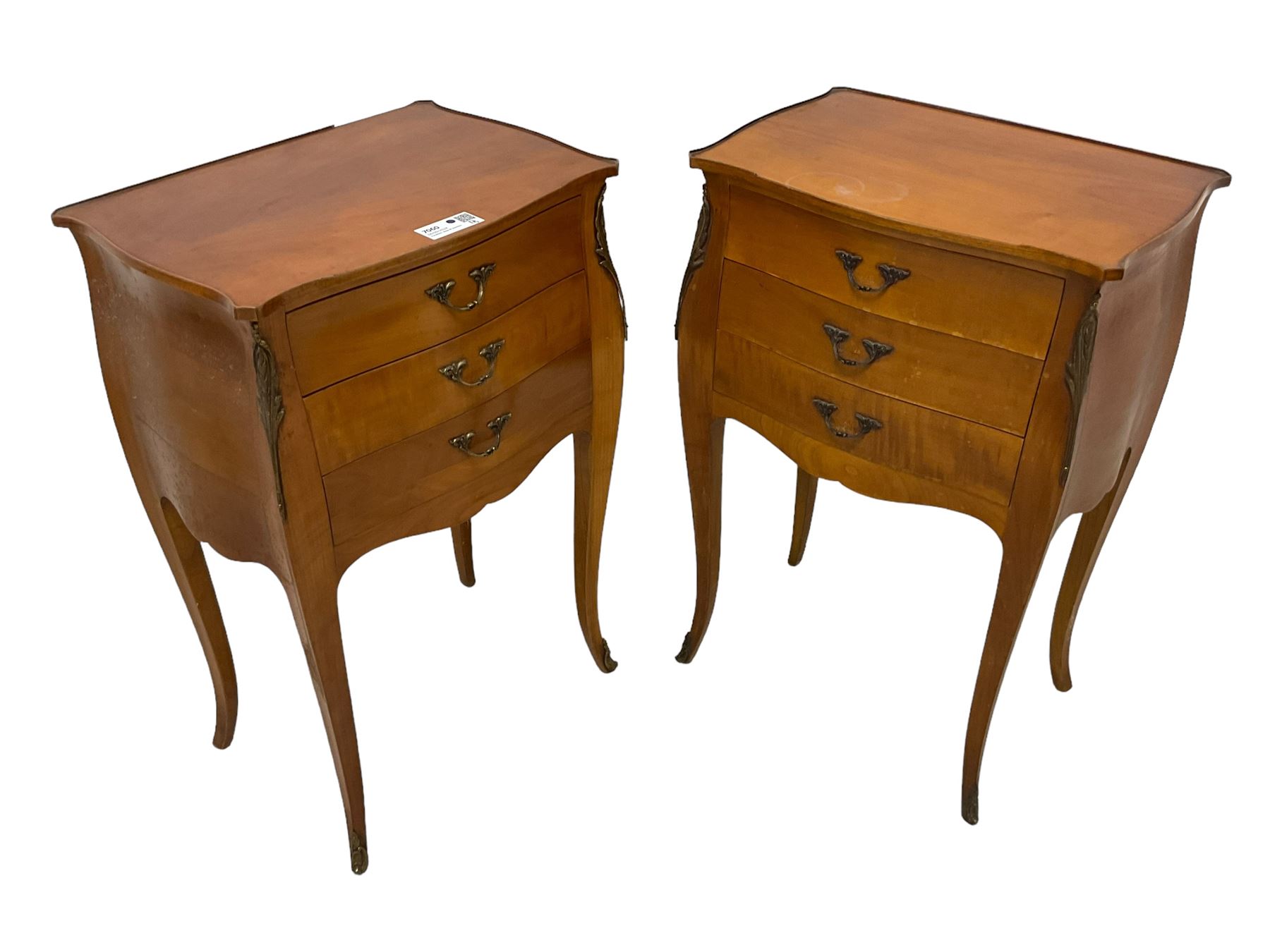 Pair of late 20th century French design cherry wood bedside lamp tables, shaped bombe form, fitted with three drawers, on tapering cabriole supports, decorated with ornate cast gilt metal mounts 