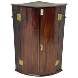 George III mahogany bow-front corner cupboard, enclosed by two figured doors with brass hinges and escutcheon, the painted interior fitted with three shelves 