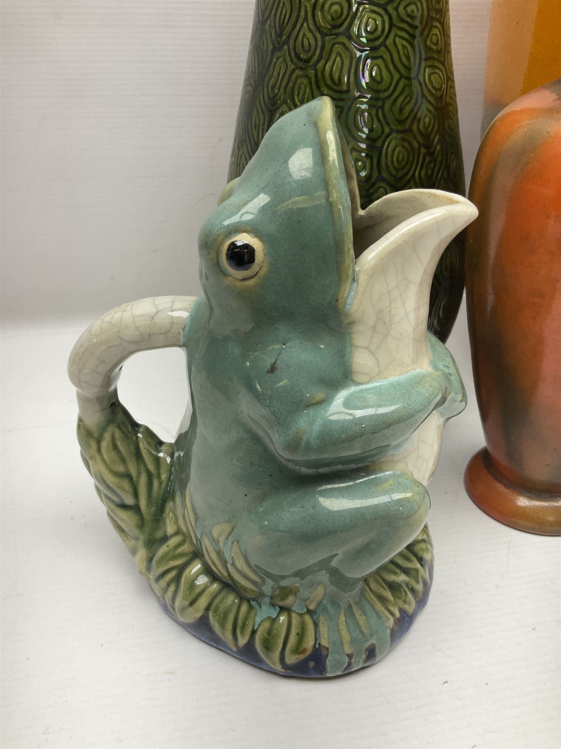 Burmantofts Faience vase, with elongated neck, and concentric circle decoration, in a green lustre glaze, together with a Bretby figure, modelled as a cat with a ball of wool, a Bretby vase, with fluted rim, in orange/red glaze, frog jug and a large West German vase, tallest H38cm