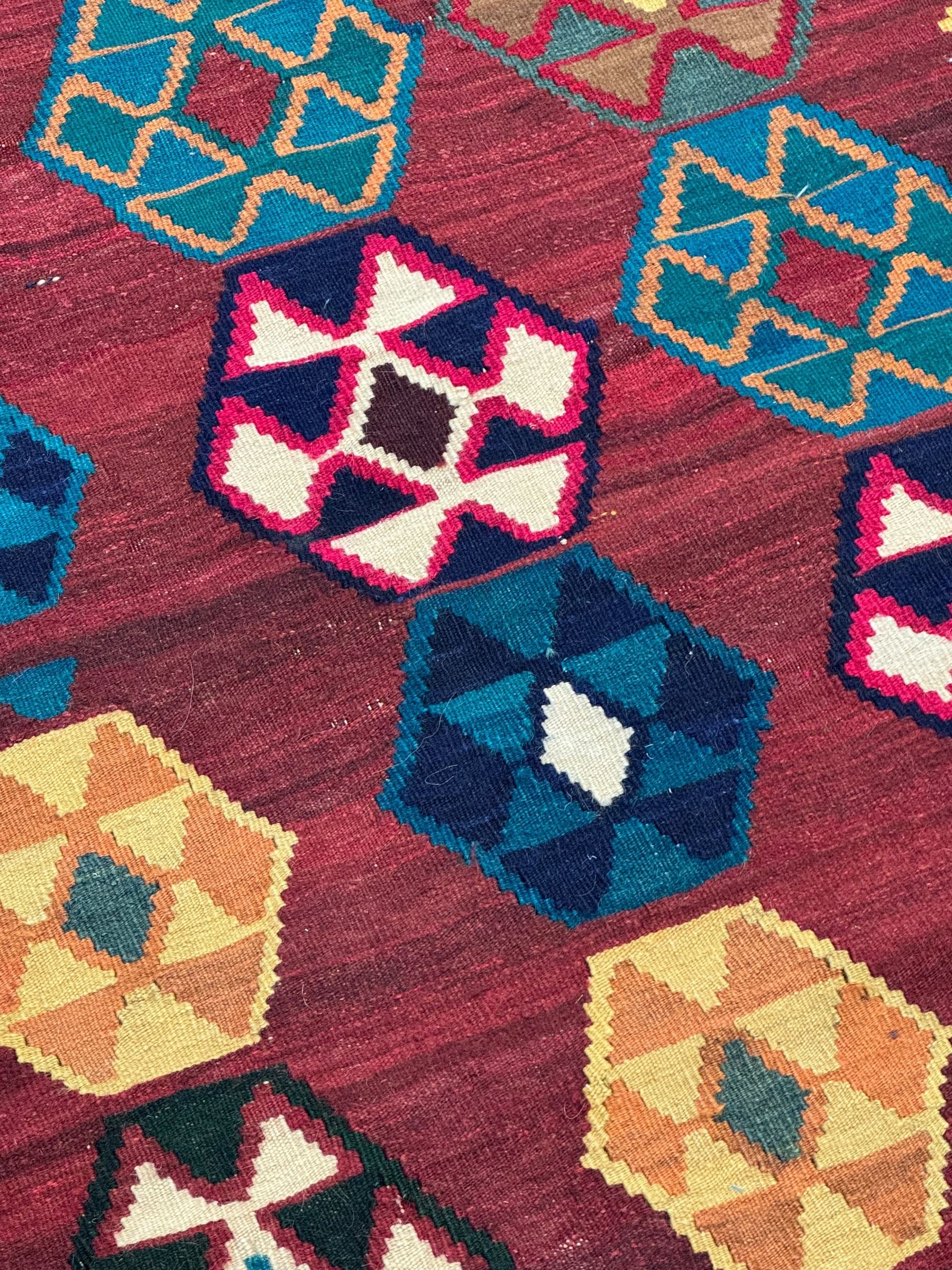 South West Persian Qashqai Kilim, crimson ground and decorated with three rows of geometric motifs, within zig-zag borders 