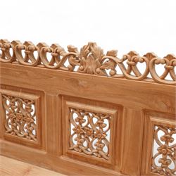 Hand carved teak garden bench, C-scroll and foliate carved cresting rail over four pierced and flower head carved panels, shaped and scrolling end supports carved with flower heads and curling leafy branches, united by pegged stretcher