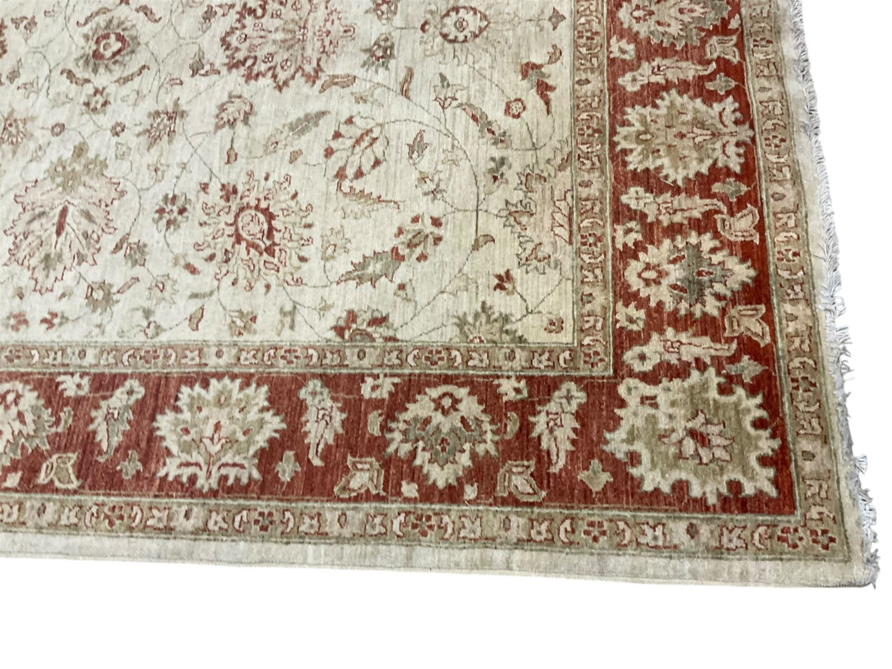 Persian Zeigler beige ground rug, the field decorated with large palmette motifs interconnected with scrolling foliate and branches, enclosed by a wide crimson guard band with repeating stylised plant motifs