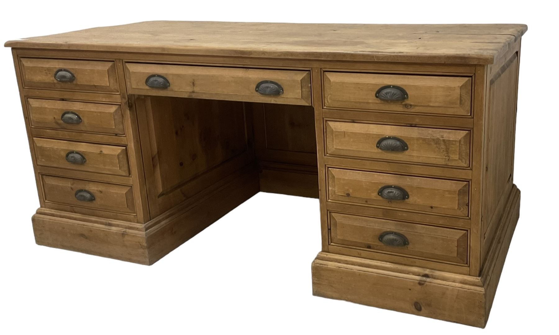 20th century waxed pine kneehole desk, rectangular top over nine drawers with cup handles, on moulded plinth base