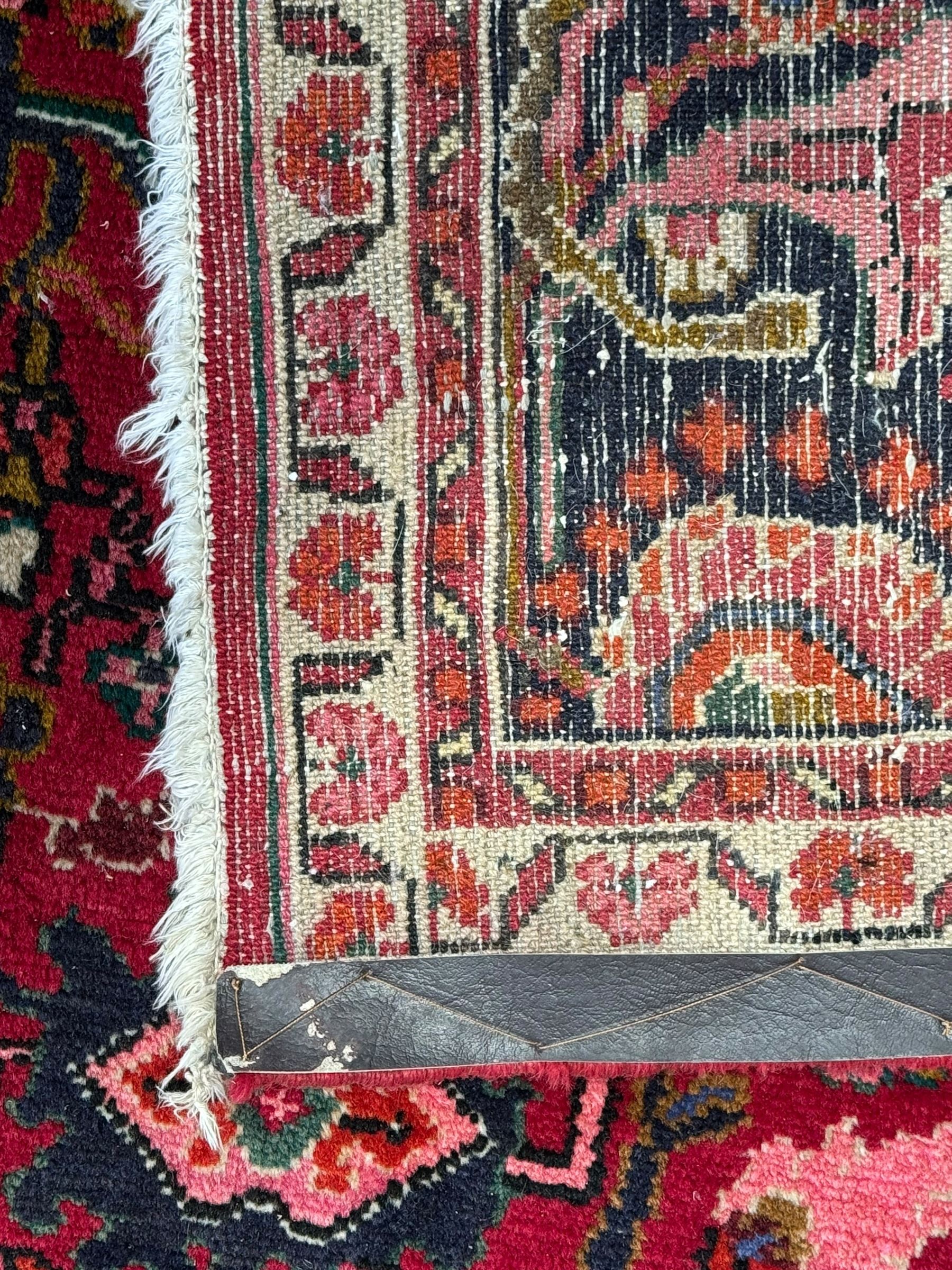 Persian Nanaj crimson ground carpet, the busy field filled with interconnecting stylised plant motifs with scrolling branches, the guarded indigo border decorated with repeating palmettes and foliate patterns