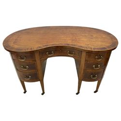 Edwardian mahogany and satinwood banded kidney-shaped writing desk, the shaped top with figured mahogany banding and boxwood stringing, fitted with seven drawers with satinwood bandings, on square tapering supports with brass and ceramic castors