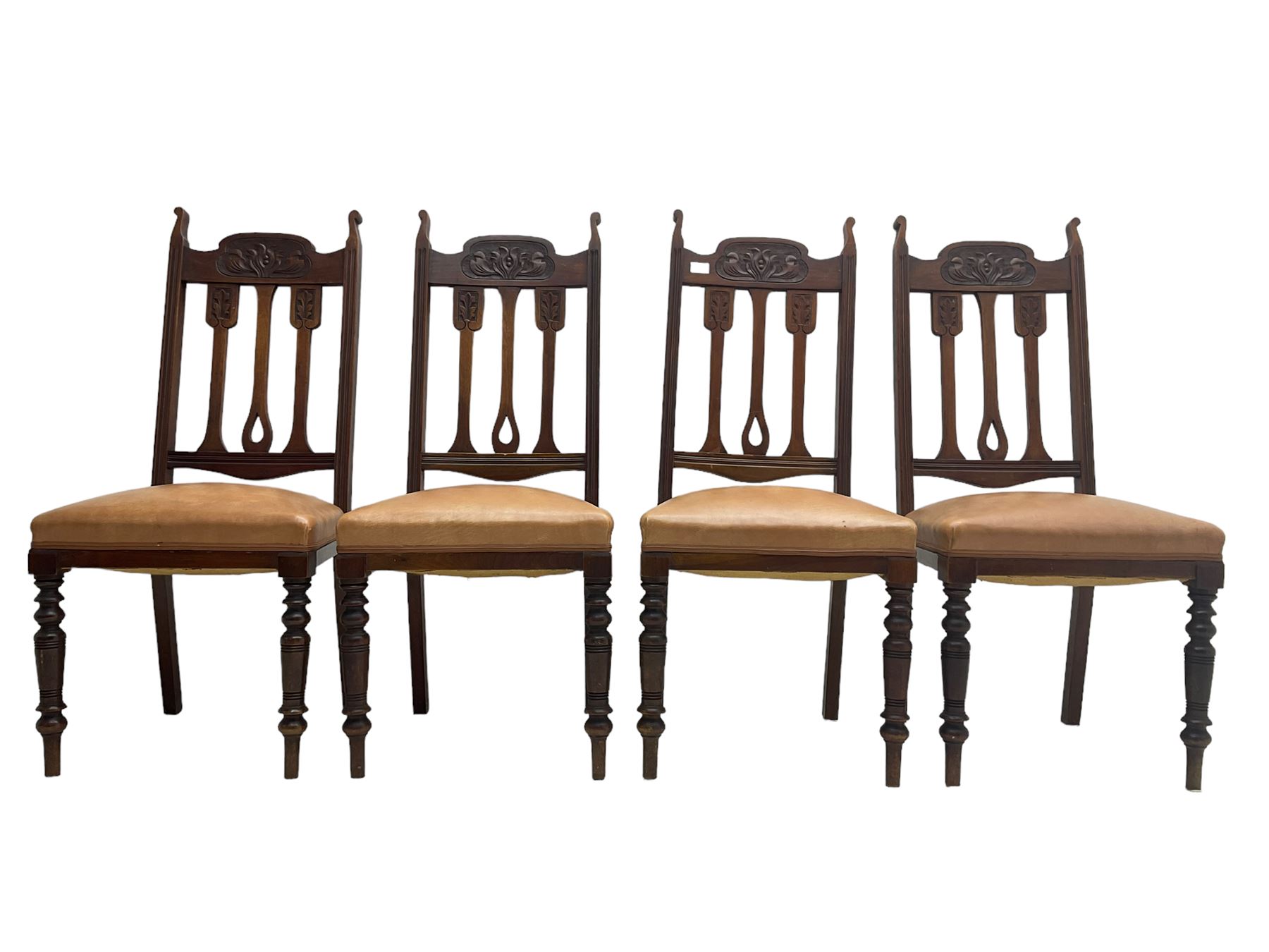 Set of four Edwardian walnut dining chairs, foliate carved high back over sprung seat upholstered in tan faux leather, raised on turned supports