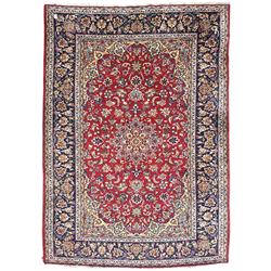 Persian Kashan red ground rug, the field decorated with a central floral medallion surrounded buy scrolling vine motifs and palmettes, the main border featuring a series of stylised floral motifs against a dark blue ground, enclosed by multiple guard stripes with alternating floral and geometric designs