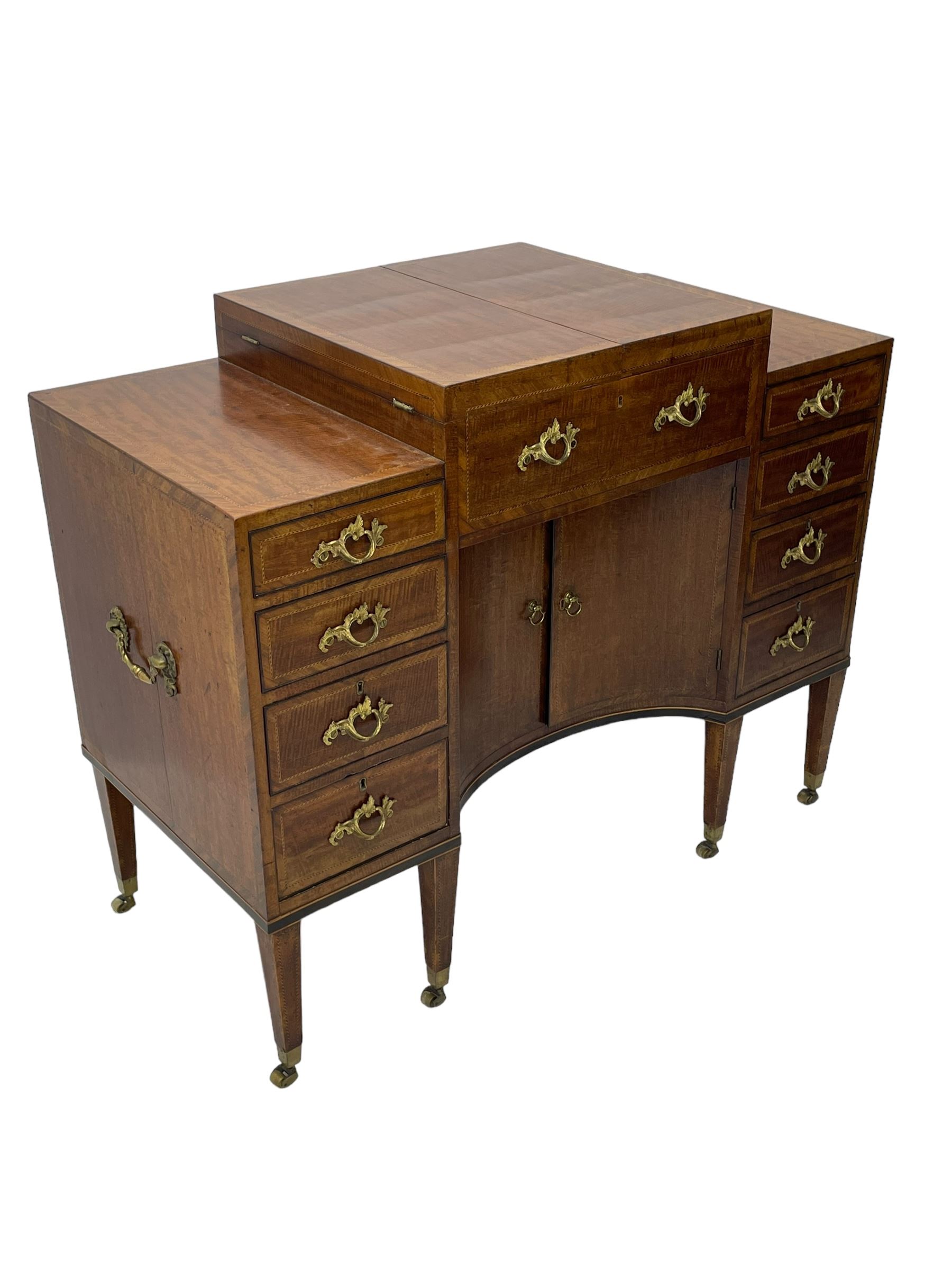 Late 19th century mahogany and satinwood dressing chest, the raised middle section hinges to reveal an interior fitted with lidded compartments, removable tray, single drawer and glass scent bottles, lift-up bevelled mirror with adjustable hinged mechanism, fitted with a further eight cock-beaded graduating drawers and curved kneehole with double cupboard, square tapering supports on brass cups and castors, inlaid throughout with checkered stringing, ornate Rococo cast gilt metal handles