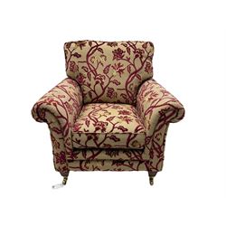 Contemporary upholstered armchair, scroll arms and loose cushions, embossed beige ground fabric with red and gold floral motifs, on tapered wooden supports with front brass castors