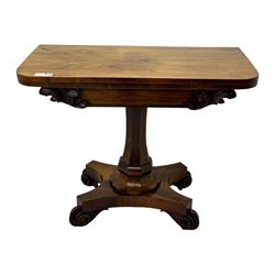 Early Victorian rosewood card table, rectangular foldover swivel top with rounded corners, red baize-lined surface, frieze adorned with carved foliate motifs, supported by a central octagonal waisted column on shaped quatrefoil base, terminating in scrolled feet with concealed metal castors