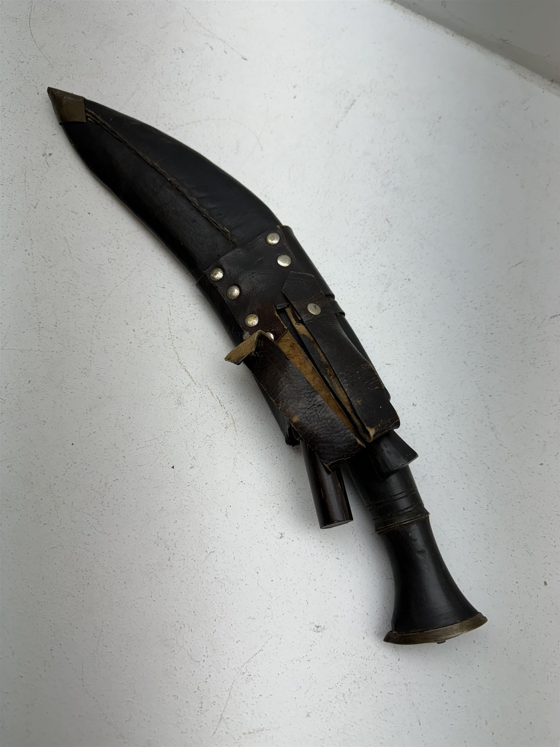 British Service issued Kukri, circa 1980s, with curving blade, hardwood and brass grip in leather covered scabbard with two skinning knives, blade, stamped 12th  December 1980 Dharan Nepal to blade, blade L28cm, overall L39cm