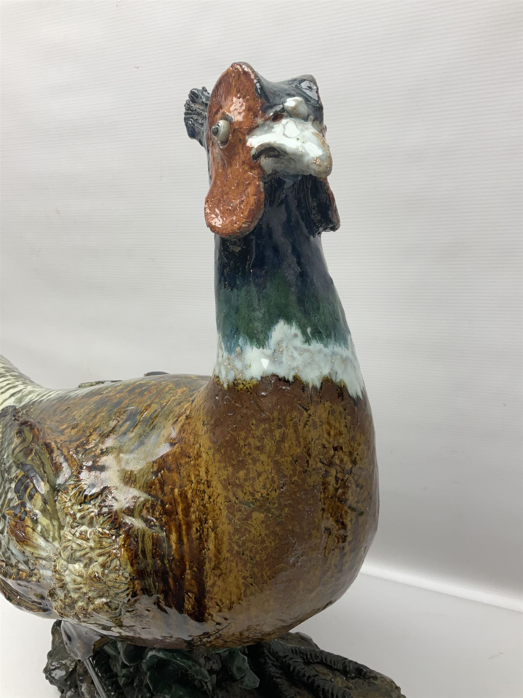 Large stoneware sculpture modeled as a Ring Neck Pheasant, upon a naturalistic base, H55cm, L78cm