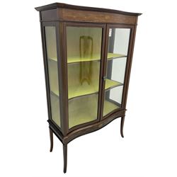 Edwardian inlaid mahogany serpentine display cabinet, projecting moulded cornice over figured frieze inlaid with tailing bellflowers and central fan motif, enclosed by two glazed doors, on square tapering supports with splayed terminals 