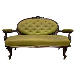 Victorian carved walnut framed two seat settee, cresting rail carved and moulded with a posy of roses and trailing foliate, over an oval back with scrolled arm terminals, serpentine fronted seat over cabriole supports with bell-flower carved knees, buttoned back and sprung seat upholstered in olive green fabric