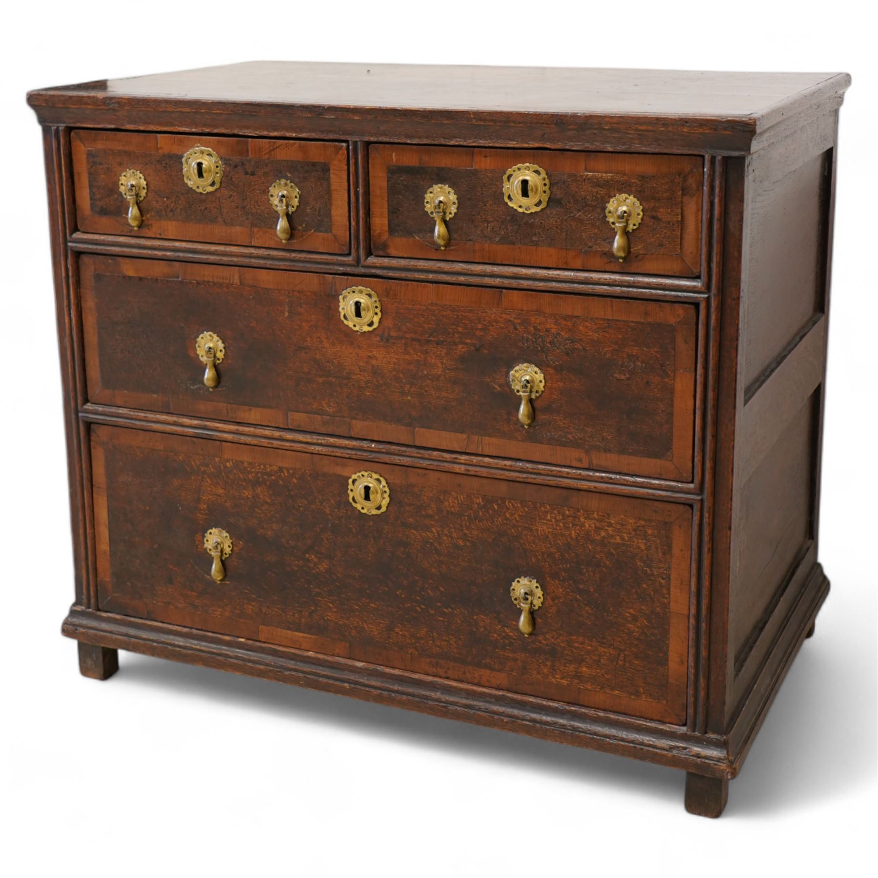 Early 18th century oak chest, rectangular top over two short and two long drawers with yew wood bands, shaped handles and escutcheons with drop handles, on stile supports 