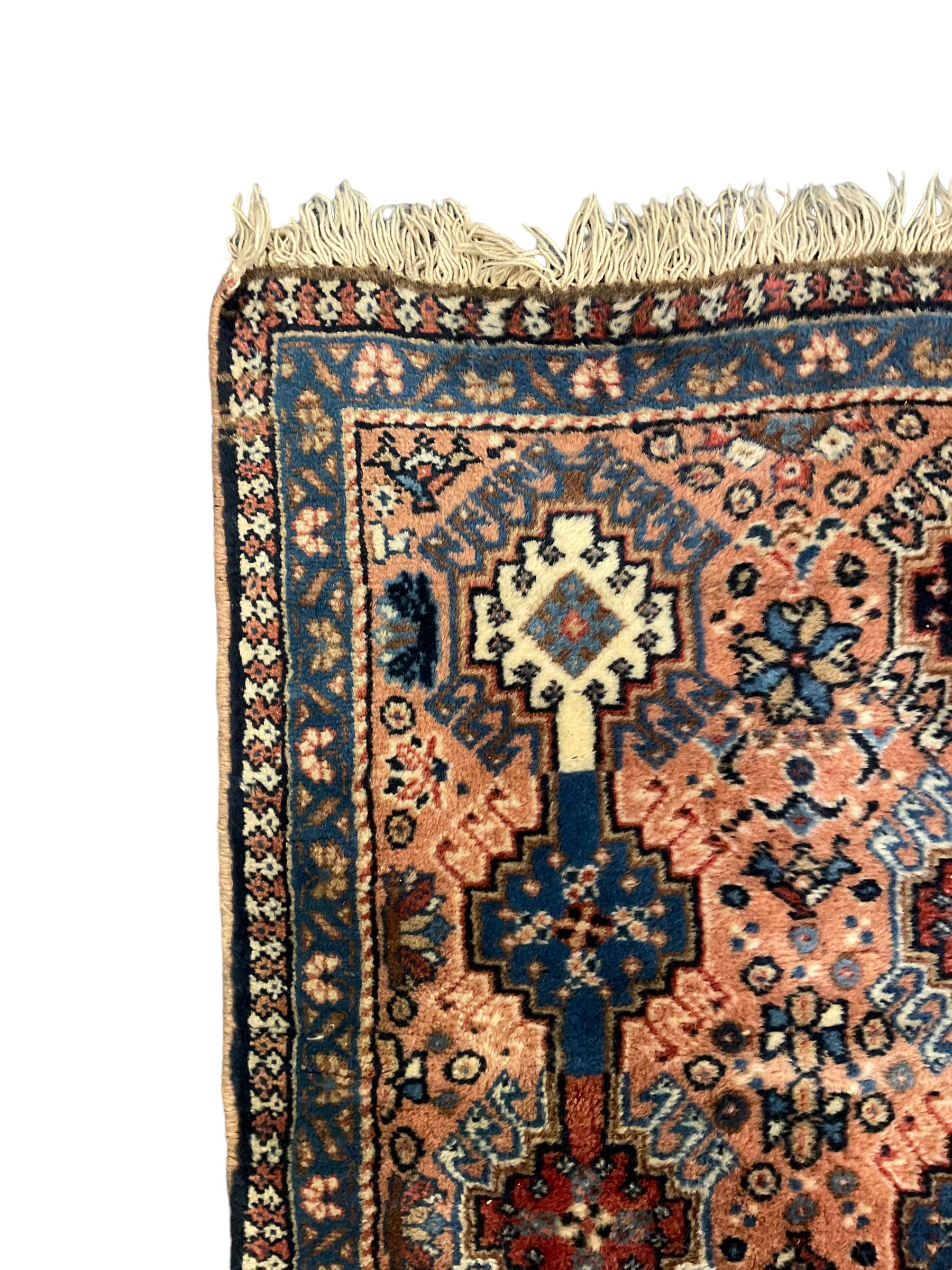 Persian prayer purple ground, decorated with three pointed buildings over tailing lozenge patterned field (111cm x 82cm); and a small Persian rug or mat, overall geometric design (81cm x 56cm)