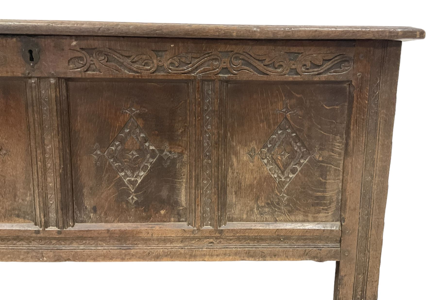 18th century oak coffer or chest, rectangular hinged panelled top with moulded frame enclosing candle box, the frieze carved with foliate S-scrolls over a quadruple panel front decorated with carved lozenges, on stile supports