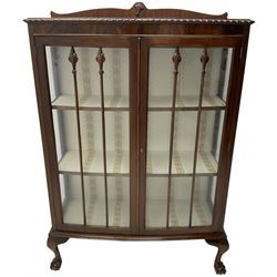 Early 20th century figured walnut bow-front display cabinet, enclosed by two glazed doors, on ball and claw cabriole feet