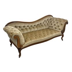 19th century walnut framed chaise longue, shaped back over scrolled arms decorated with moulded curling acanthus carvings, upholstered in deep buttoned champagne fabric, raised on cabriole supports with applied floral carved decoration, on castors