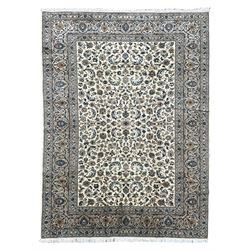 Persian Kashan ivory ground rug, overall floral design, the field decorated with scrolling foliage and palmettes, scrolling border within guard stripes decorated with small floral motifs