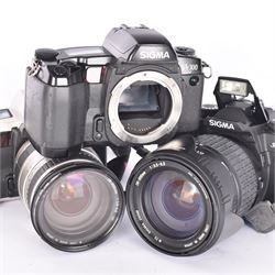 Three Sigma SLR camera bodies, to include SA-300 serial no. 8042778, SA-5 serial no. 1001611, with a Sigma 28-200mm 1:3.8-5.6 UC zoom lens, serial no. 2045647, and a Sa-7 serial no. 1002865, with a 28-300mm 1:3.5-6.3 DL Hyperzoom lens, serial no. 1003061