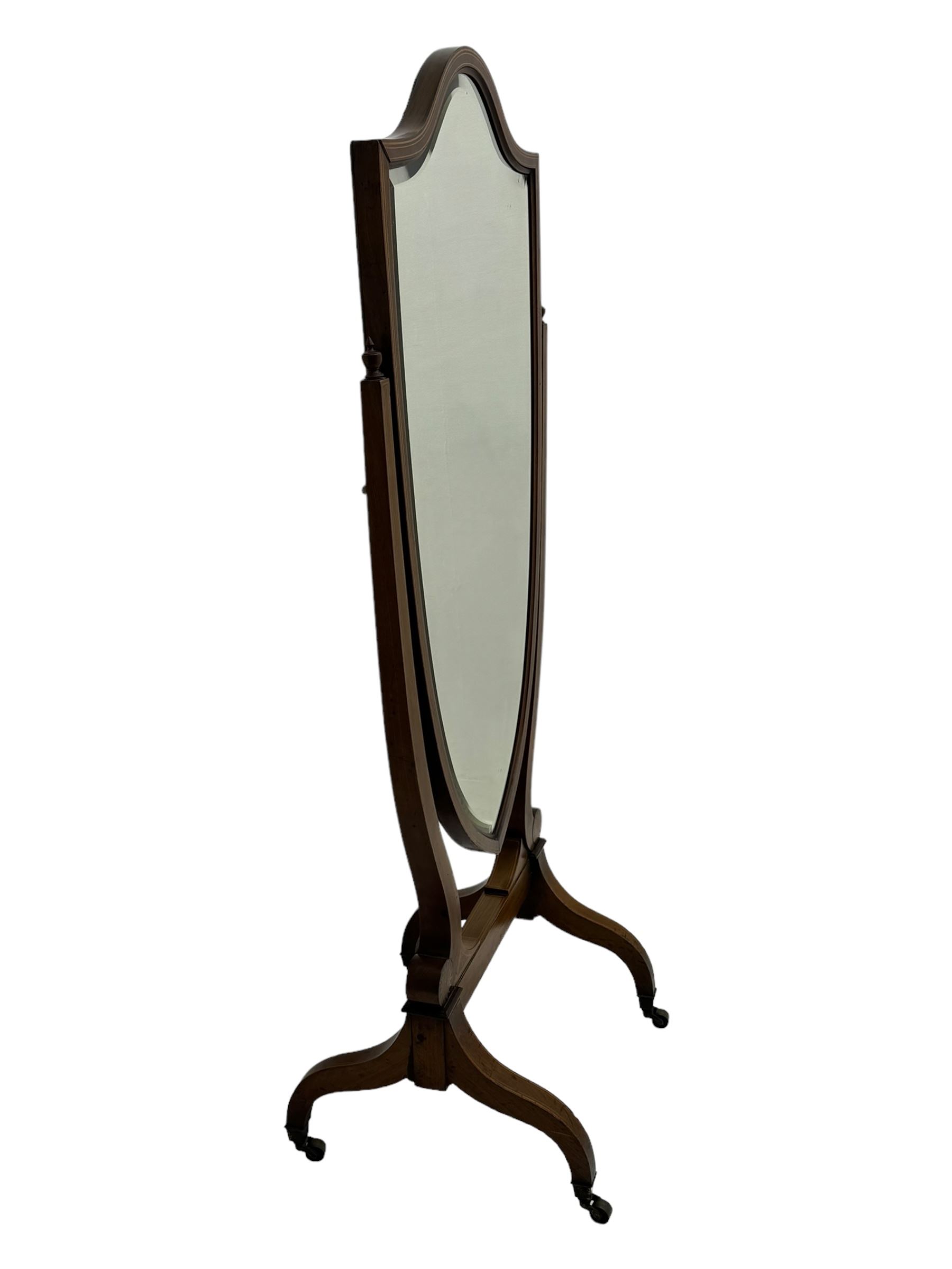 S. & H. Jewell - Edwardian mahogany cheval dressing mirror, shield shaped bevel edged mirror plate within an inlaid mahogany frame, supported by a pair of curved uprights topped with finials and terminating in a scroll design with floral inlay, the reverse bearing makers plaque, standing on four shaped supports fitted with brass castors