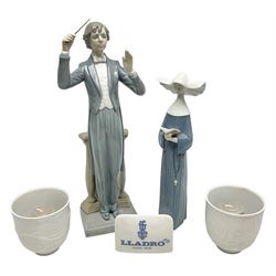 Two Lladro figures, comprising Conductor no 5196 and Prayerful Moment no 5500 together with a Lladro plaque and two Lladro candle holders, Dolphins at Play no 17666 and Sailing the Seas no 17665, all with original boxes, largest example H33cm 