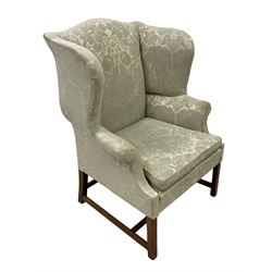 Georgian mahogany framed wingback armchair, upholstered in floral pattern silk damask fabric, wide seat enclosed by rolled arms, on chamfered square supports united by plain stretchers 