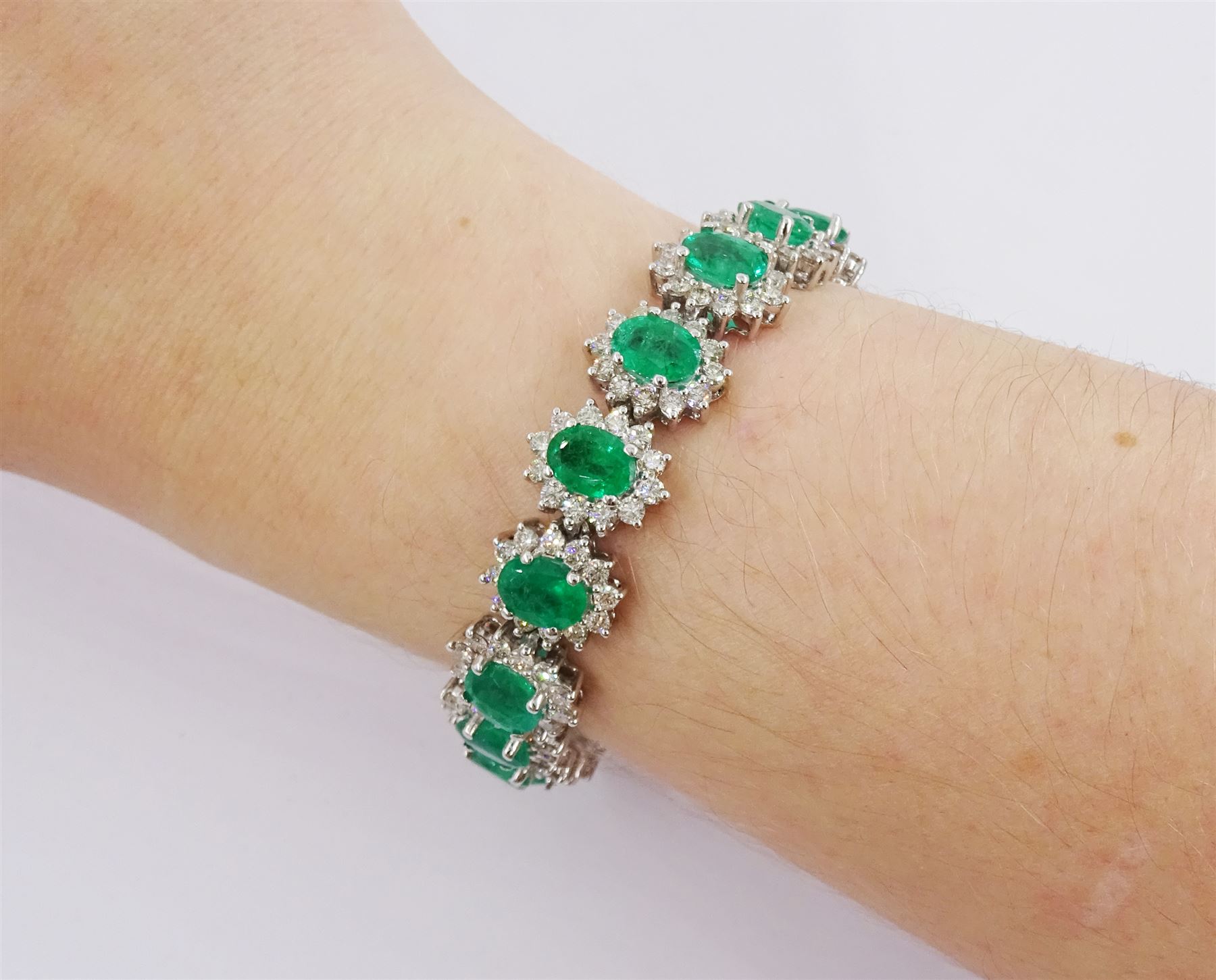 18ct white gold oval emerald and round brilliant cut diamond cluster bracelet, stamped 750, total emerald weight 14.70 carat, total diamond weight 7.24 carat