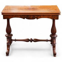 Victorian figured mahogany card table, rectangular swivel and fold-over top with rounded corners and baize lined interior, shaped apron over turned and lobe carved end supports, terminating to scroll and cartouche carved splayed supports united by swell-turned stretcher