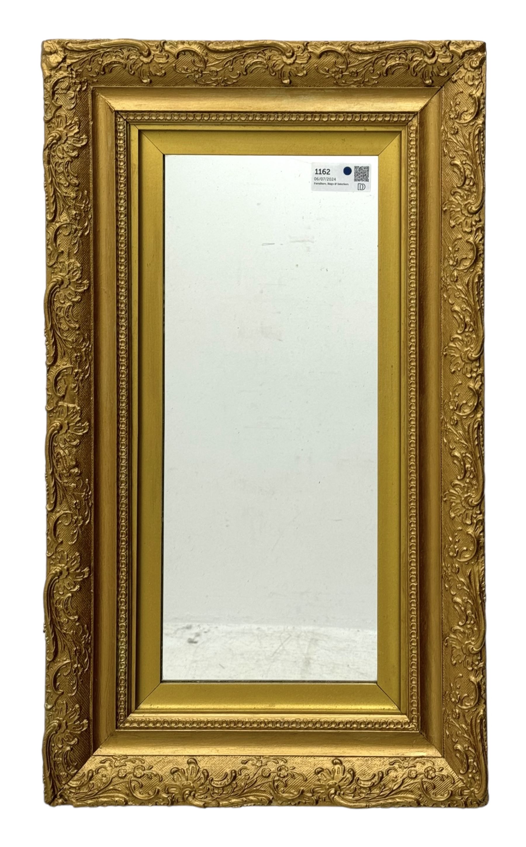 Rectangular wall mirror, in ornate gilt frame decorated with trailing leafy branches and flower heads 