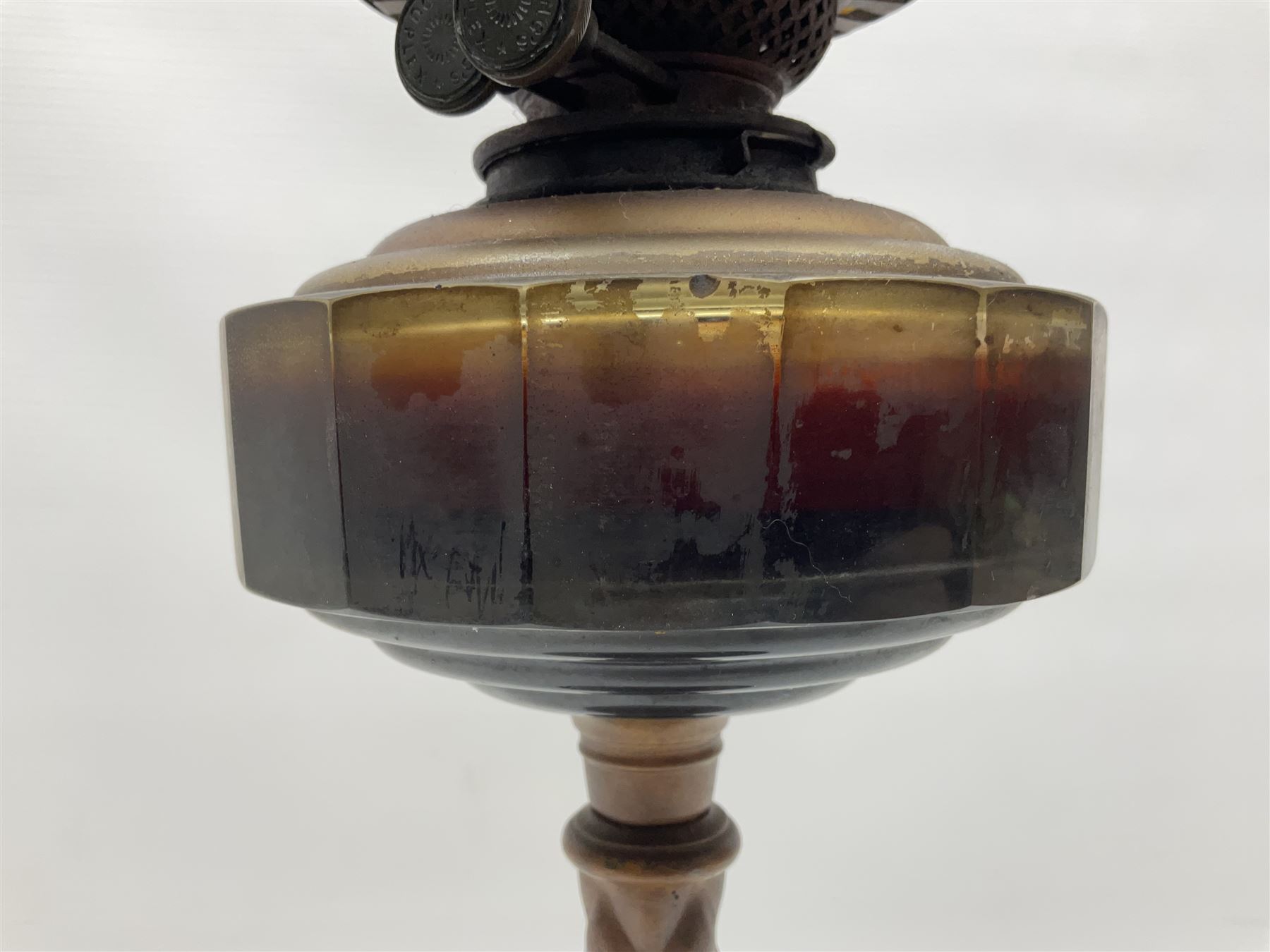 Victorian oil lamp, the faceted reservoir upon embossed copper stem and stepped circular ceramic base, with etched floral glass shade