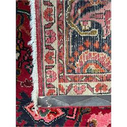 Persian Nanaj crimson ground carpet, the busy field filled with interconnecting stylised plant motifs with scrolling branches, the guarded indigo border decorated with repeating palmettes and foliate patterns