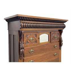 Late Victorian walnut Scotch chest, projecting cornice with turned quarter column mounts over matching half column to frieze, fitted with two upper short drawers with central cupboard, bevelled mirror glazed cupboard door, four graduating drawers below, foliage and flower head carved brackets to the uprights, panelled sides, chamfered plinth on turned feet