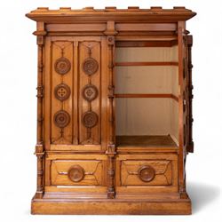 19th century pitch pine ecclesiastical vestment wardrobe or sacristy cabinet, crenelated and projecting moulded cornice over two panelled doors, the panelled doors carved with linen folds and mounted with rows of roundels depicting crucifixes and flower heads, enclosed by turned pilasters, two drawers to the base, on moulded plinth base 