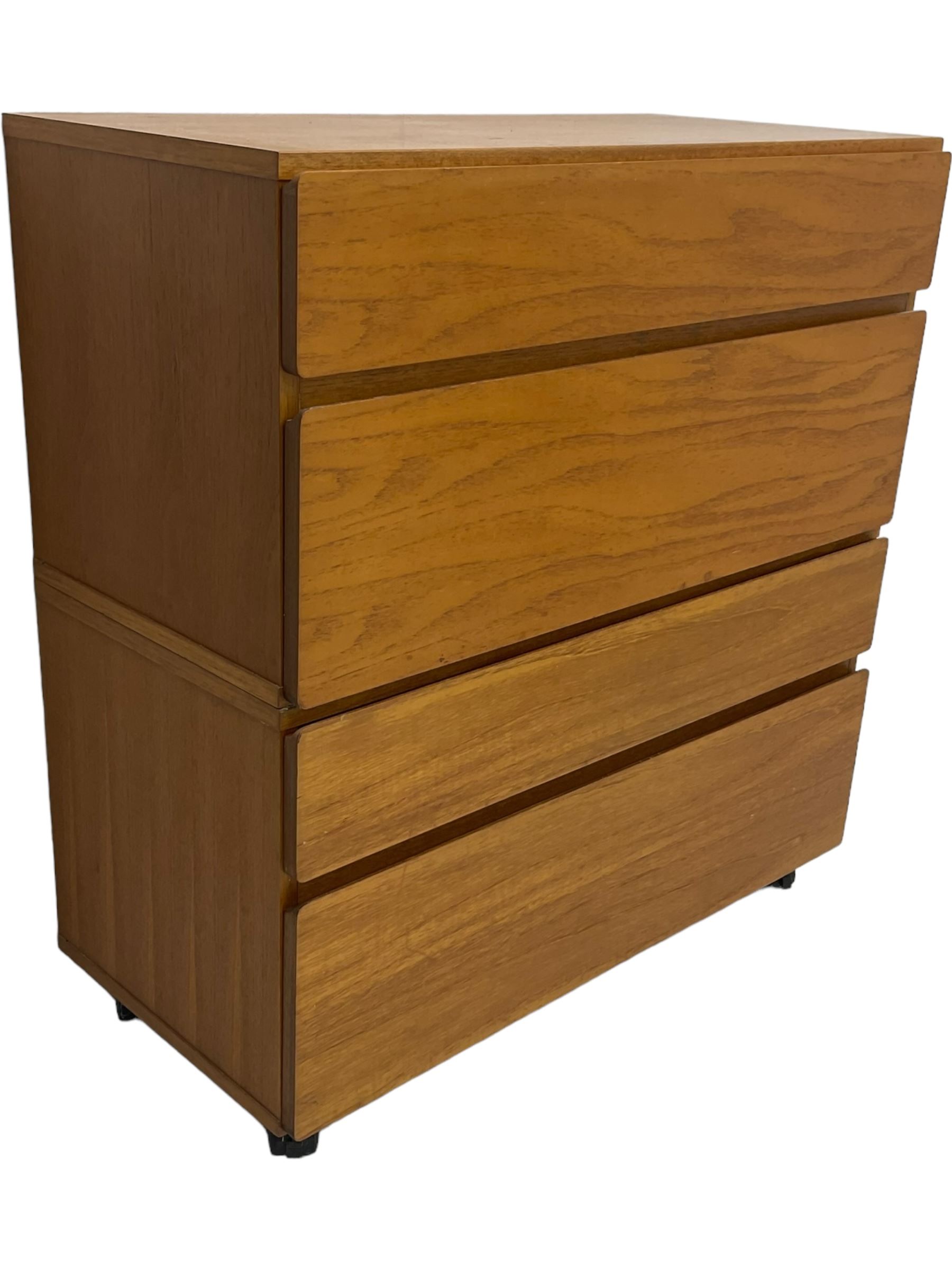 Mid-20th century teak four-drawer chest, featuring a minimalist design with two shallow and two deep flush drawer fronts, each with recessed handles along the top edge, the drawers open to reveal white laminate interiors, supported by castors