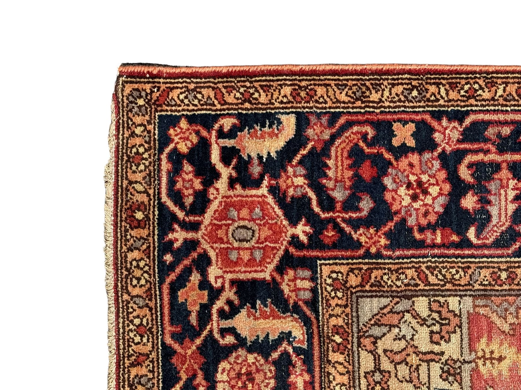 Persian Heriz design rug with red ground, the field featuring a central medallion with floral and geometric motifs, surrounded by ivory spandrels, the main border showcasing a series of floral patterns on a dark blue ground