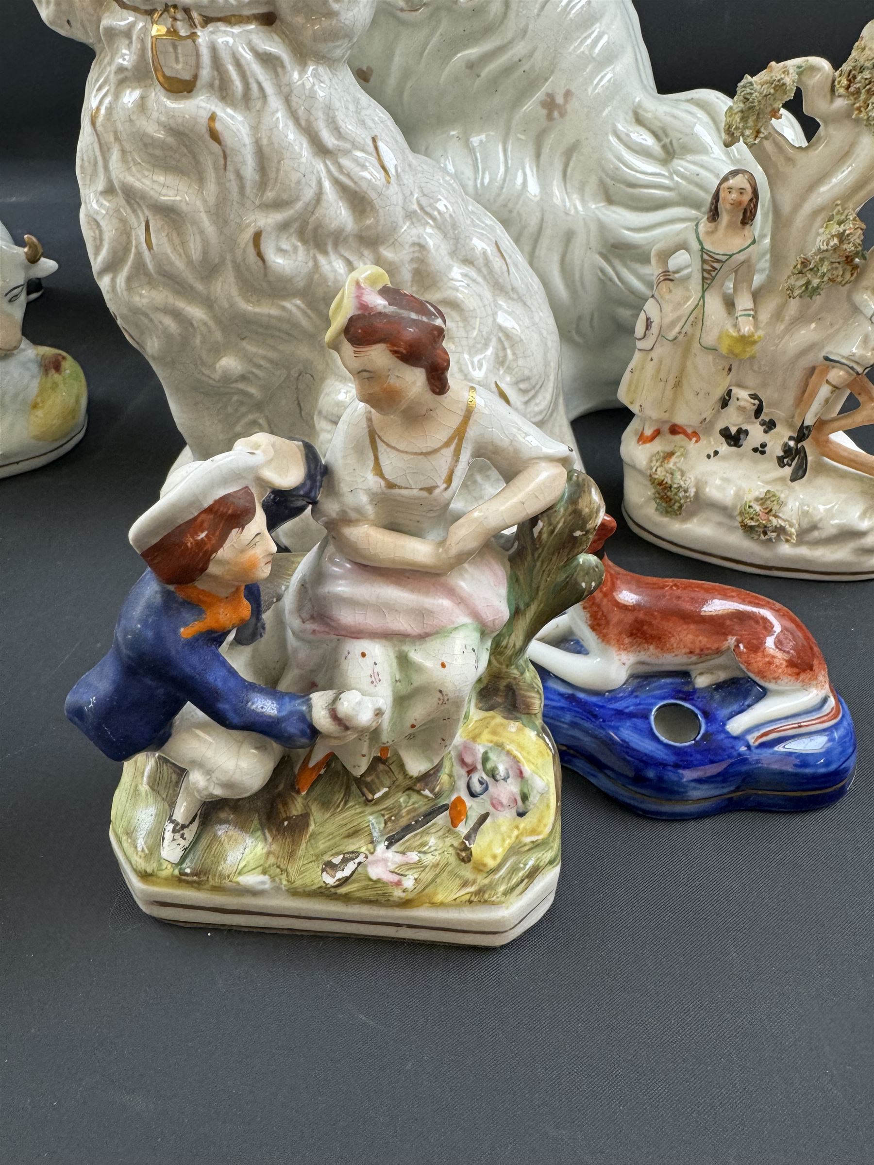 Staffordshire and Staffordshire style figures, to include a chained hound upon a blue oval base in the manner of Samuel Alcock, two pairs of seated Spaniels, a pair modelled as male figure and milk maid with cows, pair of recumbent Greyhounds, etc.