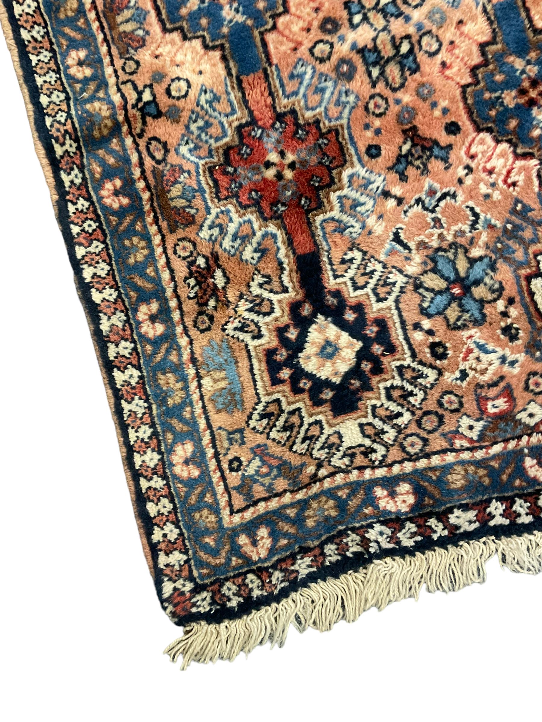 Persian prayer purple ground, decorated with three pointed buildings over tailing lozenge patterned field (111cm x 82cm); and a small Persian rug or mat, overall geometric design (81cm x 56cm)