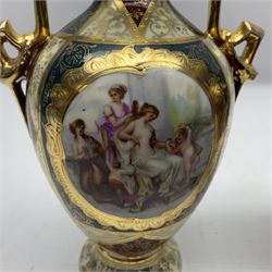 Pair of Vienna style twin handled urns and covers, decorated with figural scene on green, red and white ground with gilt highlights, stamped with beehive mark beneath, H25cm