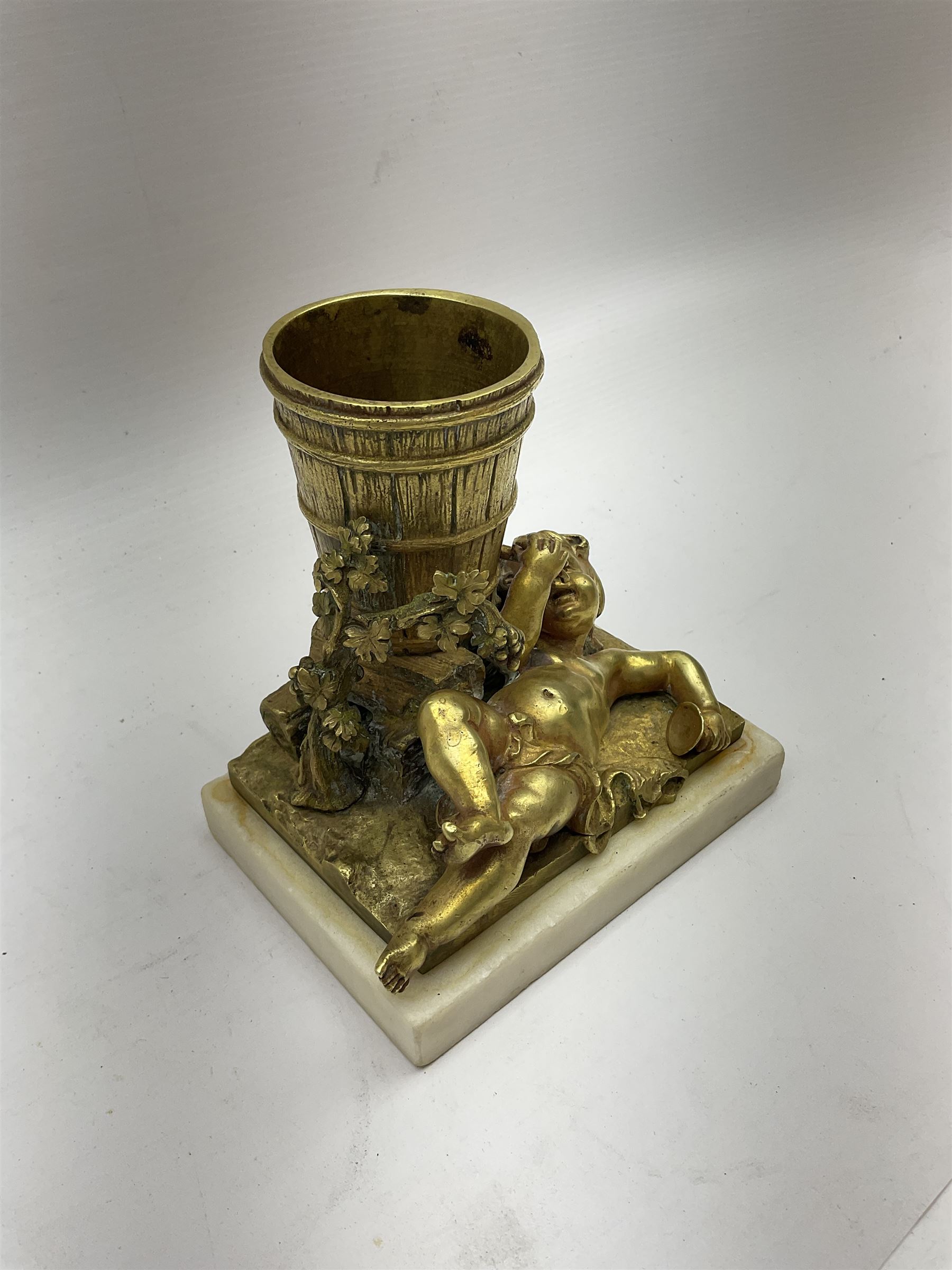 Gilt metal spill vase, the vase modelled as a a barrel with putti amongst fruiting vines laid before, upon rectangular base and rectangular marble plinth, H13.5cm