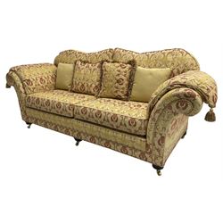 Steed Upholstery Ltd. - 'Lincoln' three-seat sofa upholstered in gold 'Olympia' floral pattern corded and tasselled fabric, together with scatter cushions and arm covers, on turned feet with brass castors