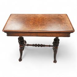 Victorian figured walnut card table, moulded rectangular fold-over swivel top with baize-lined interior, on twin turned pillar supports carved with stylised foliate motifs, united by turned stretcher, on splayed shaped feet with scrolled carved terminals, brass and ceramic castors 