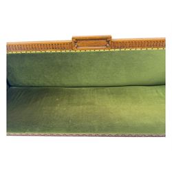 Late Victorian walnut framed sofa, rectangular backrest with carved detailing and central motif, upholstered in olive green fabric with brass studded trim and patterned front rail, scrolled fluted arms supported by turned uprights terminating in bun feet