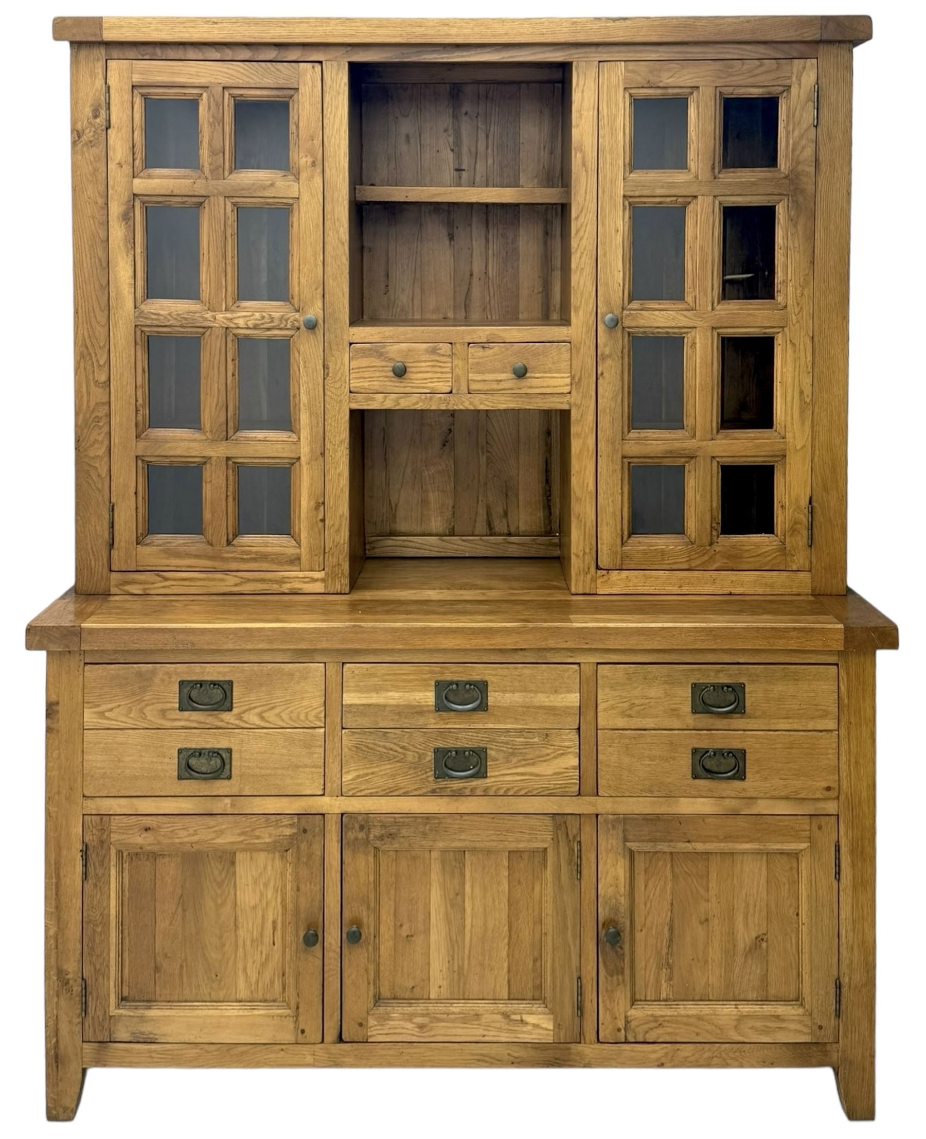 Oak dresser, upper section with twin glazed cupboard doors and central shelving with two trinket drawers, lower section fitted with six drawers over three panelled cupboard doors, raised on shaped feet 