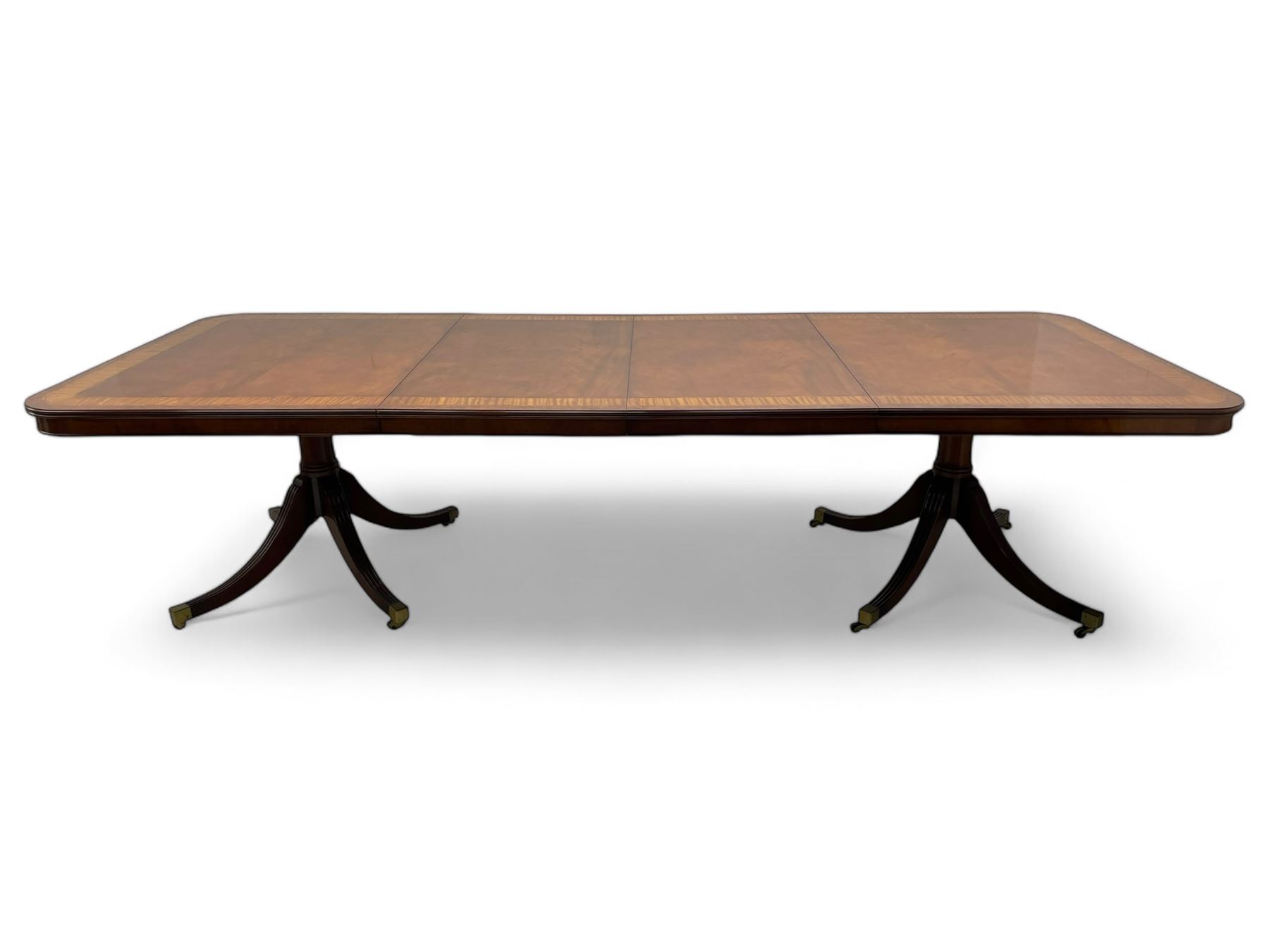 RBC Furniture (Made in England) - Georgian design mahogany dining table, rectangular top with rounded corners, satinwood and burr walnut bandings, two D-ends with two additional leaves and support rails, on barrel turned pedestals with four out-splayed reeded supports, brass cups and castors 