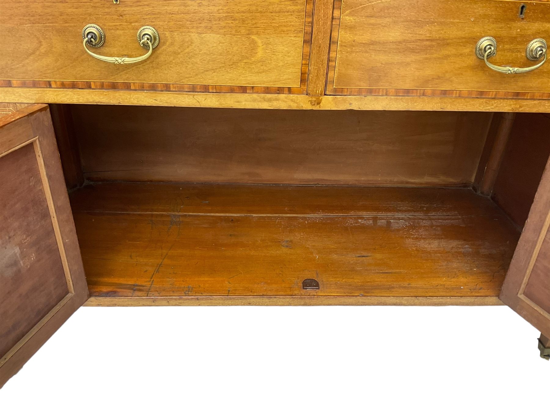 Early 20th century inlaid mahogany cabinet, two-door upper section revealing interior shelving and two large pull-out drawers, the lower section comprises two wide drawers flanked by inlaid floral motif panels above a double-door cupboard, supported by tapering legs with brass castors