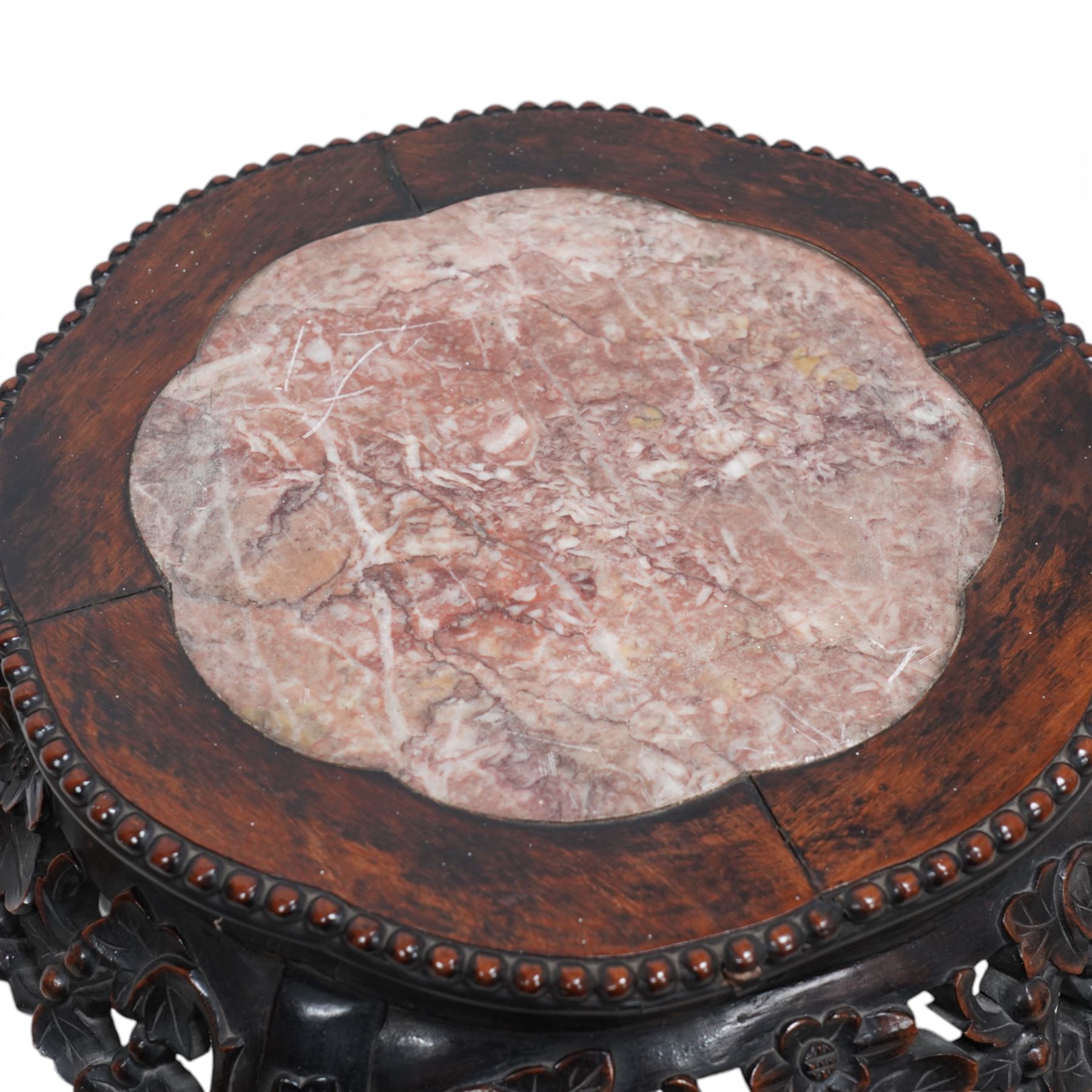 Early 20th century Chinese hardwood and marble top jardiniere or urn stand, shaped circular top with central marble inset and bead edge, over pierced and carved foliate rails with blossom design, the cabriole supports carved with trailing vines and leafage, united by X-stretcher on shaped claw feet