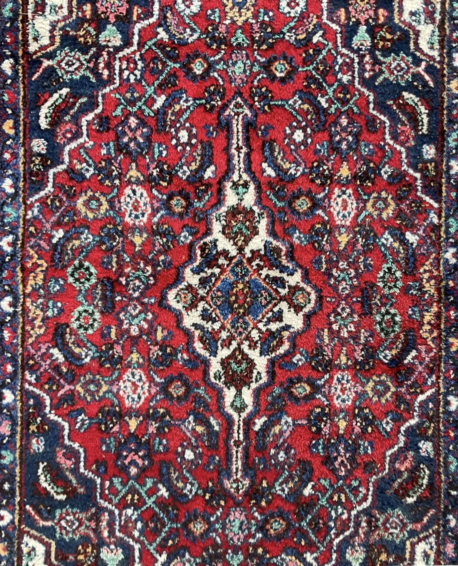 Persian Herati crimson ground rug, central ivory pole medallion surrounded by Herati motifs, with contrasting indigo spandrels, multi-band border with interlaced flowerheads